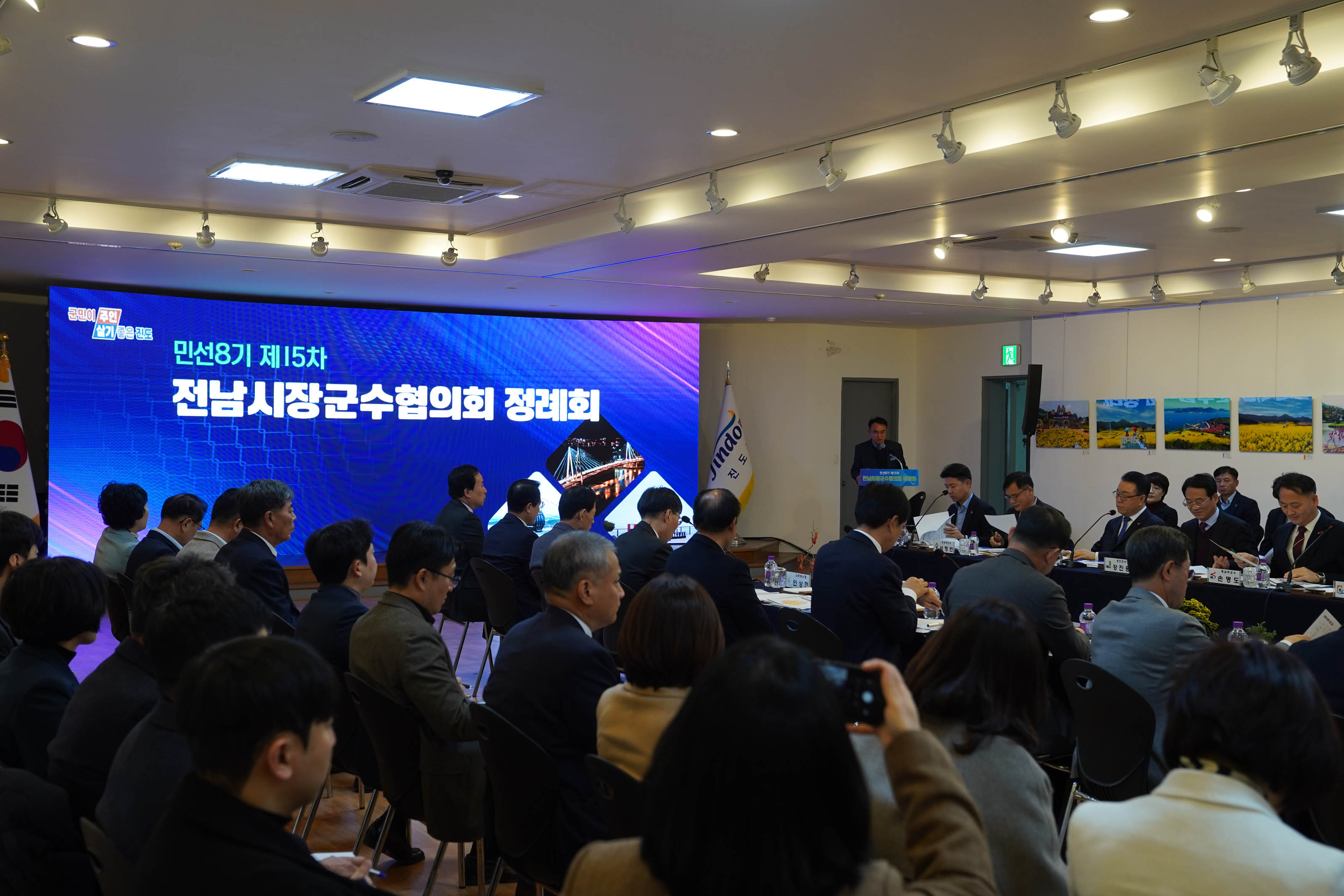'민선8기 제15차 전남시장군수협의회 정례회'라는 문구가 적힌 대형 전광판 앞에서 여러명의 관계자들이 회의를 진행 중인 모습.