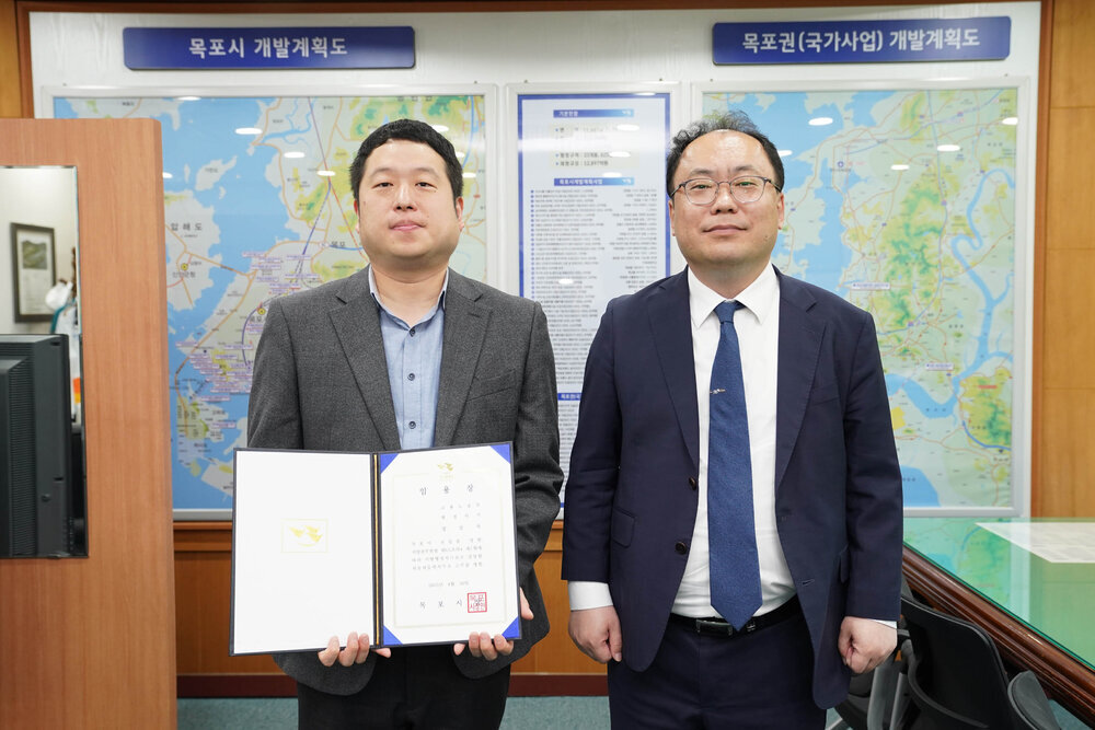 수시인사 임용장 수여식에서 정장을 입은 남성과 남성 직원이 임용장을 들고 기념촬영을 하는 모습