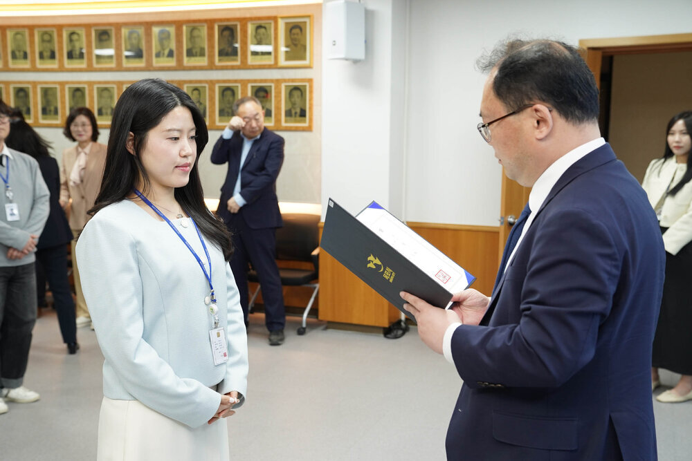 수시인사 임용장 수여식에서 정장을 입은 남성이 하늘색 블라우스를 입은 여성 직원에게 임용장을 전달하는 모습