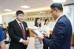 정장 차림의 관계자가 검은 정장을 입은 남성 수상자에게 표창패를 전달하는 모습이며 뒤에 다른 수상자들이 대기하고 있다.