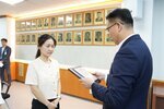 정장 차림의 관계자가 밝은색 블라우스를 입은 여성 수상자에게 표창패를 전달하며 읽고 있는 모습이다.