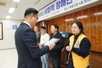 11월 정례조회로 정장을 입고 안경을 쓴 남성이 검은 셔츠에 노란색 조끼를 입고 두손을 앞으로 맞잡은 고성순 수상자에게 상패를 수여 하고 있다.